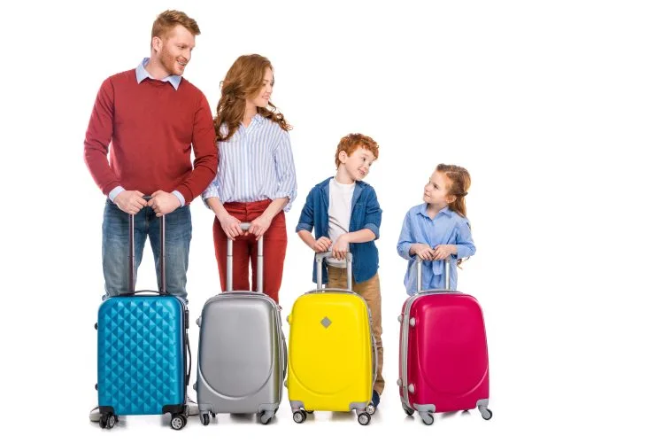 happy redhead family standing with colorful suitcases isolated on white